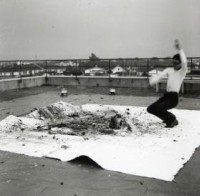 Šozo Šimamoto pravi sliku bacajući staklene flaše sa bojom na platno na Drugoj Gutai izložbi, Ohara Kaikan, Tokio, 11–17. oktobar 1956.
